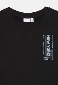 Felpa nera in cotone con scollatura rotonda. Testo grafico azzurro chiaro "NEW YORK 1982 CORE" con accenti a strisce sulla parte frontale.