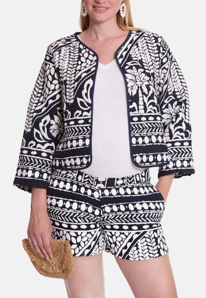 Marineblauwe en witte outfit met patroon, bestaande uit een cropped jack met botanische ontwerpen en bijpassende shorts; inclusief een geweven clutch.