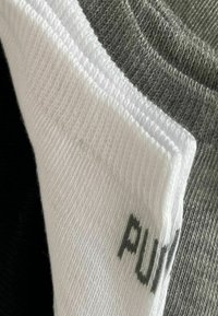 Three pairs of socks: one black, one grey, one white, with ribbed cuffs. White sock features "PUMA" printed in dark gray.