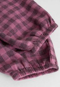 Tissu à carreaux dans des tons de rose et de gris, avec des poignets élastiqués froncés et une texture douce. Motif carré prononcé visible.