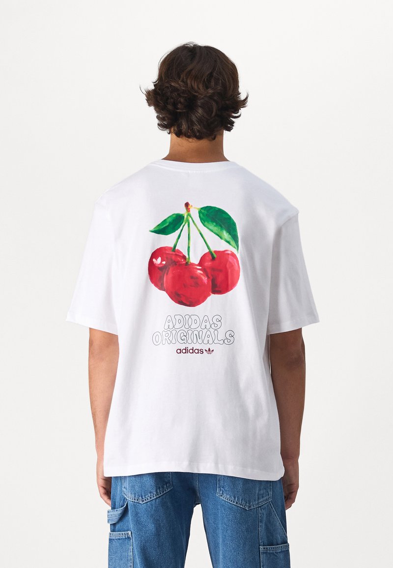 Hvid bomulds t-shirt med en farverig kirsebærgrafik på ryggen med grønne blade, og "Adidas Originals" tekst nedenunder i grå.