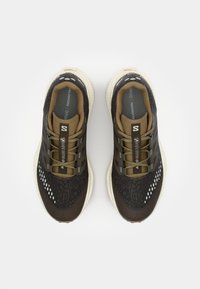 Brown and black athletic shoes featuring a textured upper, breathable mesh, and a white sole. Six metallic eyelets with laces.