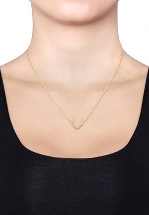 Goldkettchen mit einem Geweih-Anhänger; zartes Design mit glänzender Oberfläche und glatter Textur, getragen auf nackter Haut.