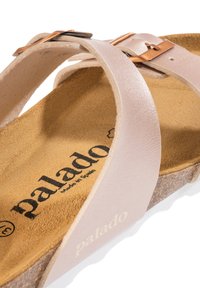 Sandaña de piel rosa claro con suela de corcho, que presenta correas ajustables y una hebilla en tono cobre. Plantilla texturizada para mayor comodidad.