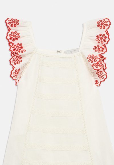Λευκό φόρεμα με κόκκινες κεντητές λουλουδένιες βολάν, με υφασματικές κάθετες ρίγες και δαντελένιες λεπτομέρειες κατά μήκος του λαιμού και του τελειώματος.