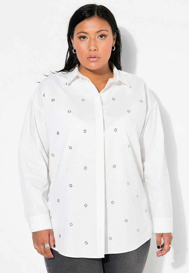 Camisa blanca de botones con embellishments circulares plateados por toda la prenda. Presenta un cuello clásico y mangas largas, hecha de una tela ligera.