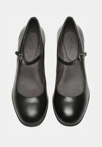 Black leather Mary Jane shoes with a low, round toe and an adjustable strap. Smooth texture with a matte finish and a contoured footbed.