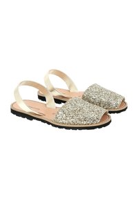 Sandales brillantes avec une finition dorée scintillante, design à bout ouvert, sangles élastiques au talon et semelles en caoutchouc noir. Intérieur en cuir lisse.