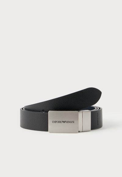 Μαύρη δερμάτινη ζώνη με υφή και ορθογώνια ασημένια αγκράφα με χαραγμένο το λογότυπο Emporio Armani, τυλιγμένη σε λευκό φόντο.