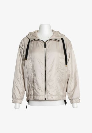 Lyse beige hættetrøjejakke med sorte snore, frontlynlås, sidelommer, elastiske manchetter med knap og elastisk kant på en hvid mannequin.
