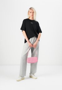 Black oversized t-shirt, gray sweatpants, cream sneakers, and a small pink textured handbag. Simple, casual outfit suitable for daily wear.