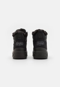 Baskets montantes noires avec col en fourrure, dotées d'une tige texturée, d'une semelle épaisse en caoutchouc et d'un logo à l'arrière.