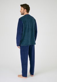 Marineblauwe lounge set met een gestreepte lange mouw top die comfortabel aanvoelt en bijpassende effen broek, ontworpen voor ontspanning.