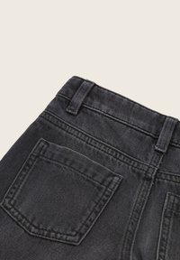 Vaqueros de mezclilla negra con una cintura alta, que cuentan con dos bolsillos traseros, tejido texturizado y costuras en contraste a lo largo de las costuras.