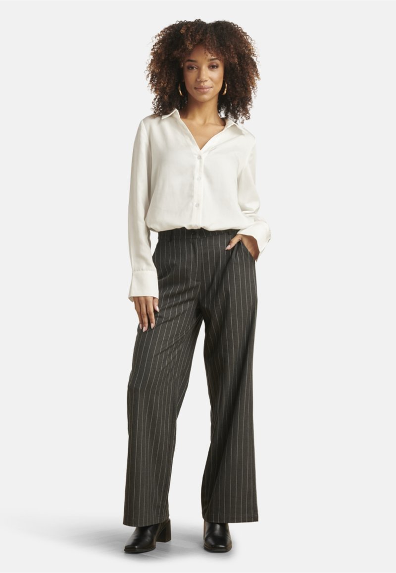 White button-up shirt, wide black pinstriped trousers, and black heeled boots. Smooth fabric with a relaxed fit and long sleeves.