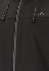 Chaqueta negra con cremallera, de textura suave, con cordón ajustable y un pequeño logo en el pecho. Presenta un diseño elegante y minimalista.