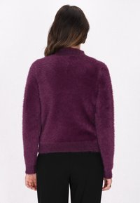 Uldent lilla sweater med rund halsudskæring og lange ærmer. Har ribbede kanter og manchetter, som fremhæver en blød tekstur.