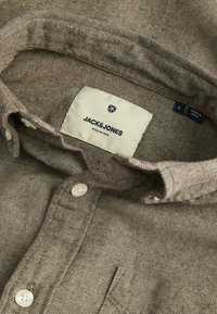 Bruine geweven kraag van een shirt met knoopsluiting. Etiket zegt "JACK & JONES PREMIUM," maat L. Heeft een subtiele textuur in de stof.