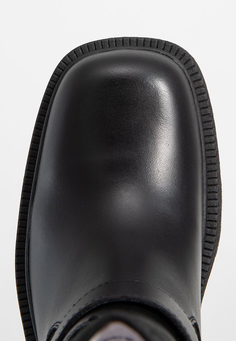 Czarne skórzane botki za kostkę z zaokrąglonym noskiem, teksturowanym detalem po bokach i żebrowaną podeszwą. Widać gładkie wykończenie oraz solidną konstrukcję.