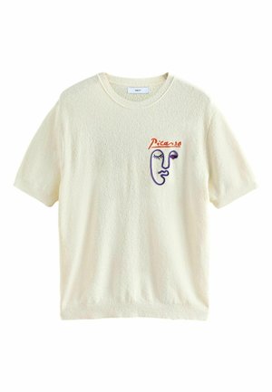T-shirt court crème à manches courtes texturé avec col rond et design abstrait brodé d'un visage en violet et rouge avec le texte « Picasso » sur le côté gauche de la poitrine.