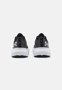 Zapatillas de correr negras con parte superior de tela texturizada, media suela blanca y suela de goma. Presenta un acento de logo en el talón y un bucle reforzado.
