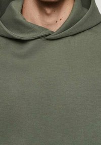 Sweat à capuche vert olive avec col montant, fabriqué en tissu doux ; présente une texture lisse sans motifs ni détails métalliques visibles.