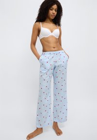 Pantalon de pyjama bleu clair avec motifs de roses rouges, doté d'une ceinture élastique et de poches latérales, fabriqué en tissu doux à rayures verticales.