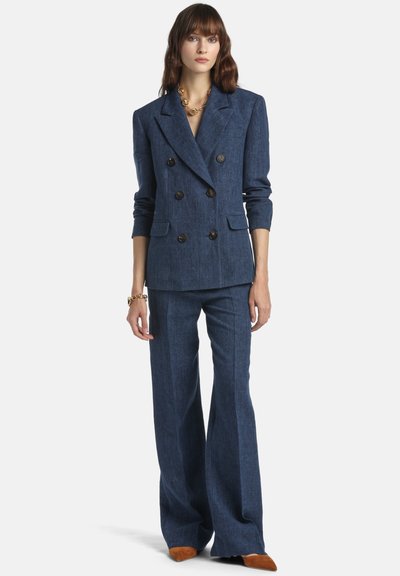 Navy denim double-breasted blazer with large buttons, matching wide-leg trousers, and a smooth texture, paired with brown suede shoes.