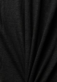 Gros plan sur un tissu en maille noir avec une texture visible et des plis subtils créant des lignes diagonales à la surface.