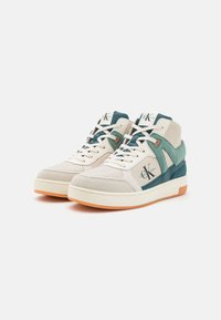 Höga sneakers i krämfärg, teal och mintgrön läder med perforerad tå, vita snören, logodetalj och orangegummisula.