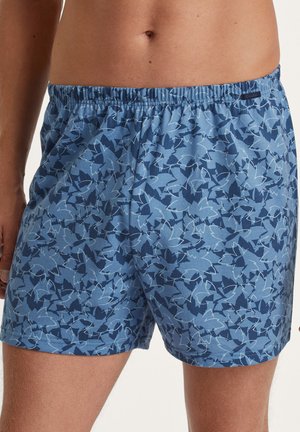 Pantaloni da bagno blu a fantasia con una combinazione di tonalità chiare e scure, una vita elastica e una texture di tessuto morbido.