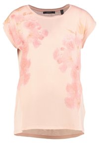 Haut rose clair à manches courtes en tissu lisse, avec un imprimé floral dans des tons de rose plus foncés sur le côté gauche, doté d'un col arrondi.