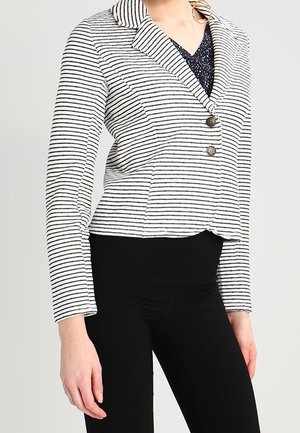 Blazer rayé en tissu léger, avec un col cranté, deux boutons en métal et une silhouette ajustée. Accentué par des rayures noires et blanches.
