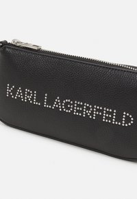 Černá kožená zipová taštička s embosovaným povrchem, kovovými detaily a zdobením z rhinestone s nápisem "KARL LAGERFELD." Hladká textura.