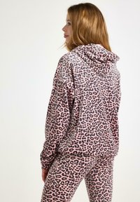 Hoodie w leopardzim wzorze w różowym i czarnym kolorze, z kieszenią kangurzą i kapturem. Tkanina jest miękka; projekt obejmuje długie rękawy i elastyczny krój.