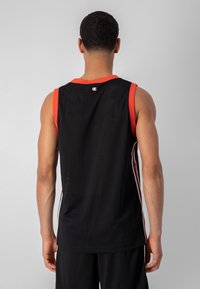 Jersey deportivo de malla negra con acentos rojos en el cuello y los agujeros de los brazos, con rayas en los paneles laterales. Diseño ligero y transpirable.