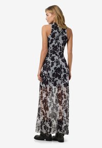 Rochie maxi din material transparent cu un model abstract în nuanțe de negru și gri, guler înalt, corset ajustat și fustă fluidă transparentă.