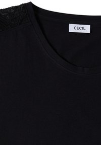 T-shirt noir à col rond avec un détail en dentelle texturée à l'épaule et une étiquette blanche mentionnant "CECIL" à l'intérieur du col.