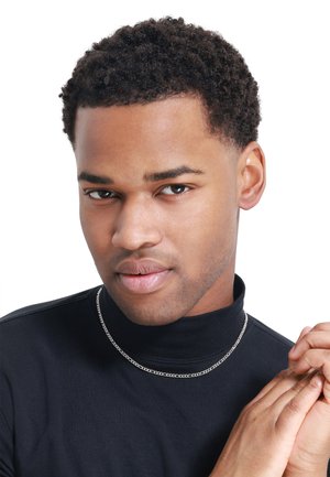 Svart turtleneck topp, sølvkjedesmykke, nærbilde av ansikt med kort, krøllete hår, nøytral bakgrunn. Glatt hud og avslappet uttrykk.