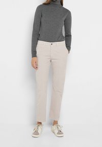 Ljust beige kordflorsebyxor med rak passform, fransad nederkant och femfickorsdesign, kombinerade med en åtsittande grå polotröja och avslappnade sneakers.