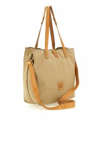 Bolso tote de lona en beige con correas de cuero color canela. Cuenta con herrajes dorados, un parche con el logo y una correa cruzada ajustable.