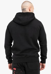 Black hoodie with a kangaroo pocket, ribbed cuffs, and hem. Features a textured fabric and a drawstring hood. Minimalist design with no logos.