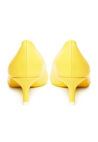 Zapatos de tacón alto de cuero amarillo con puntera afilada y un tacón delgado y estructurado. Textura suave sin embellecimientos visibles.
