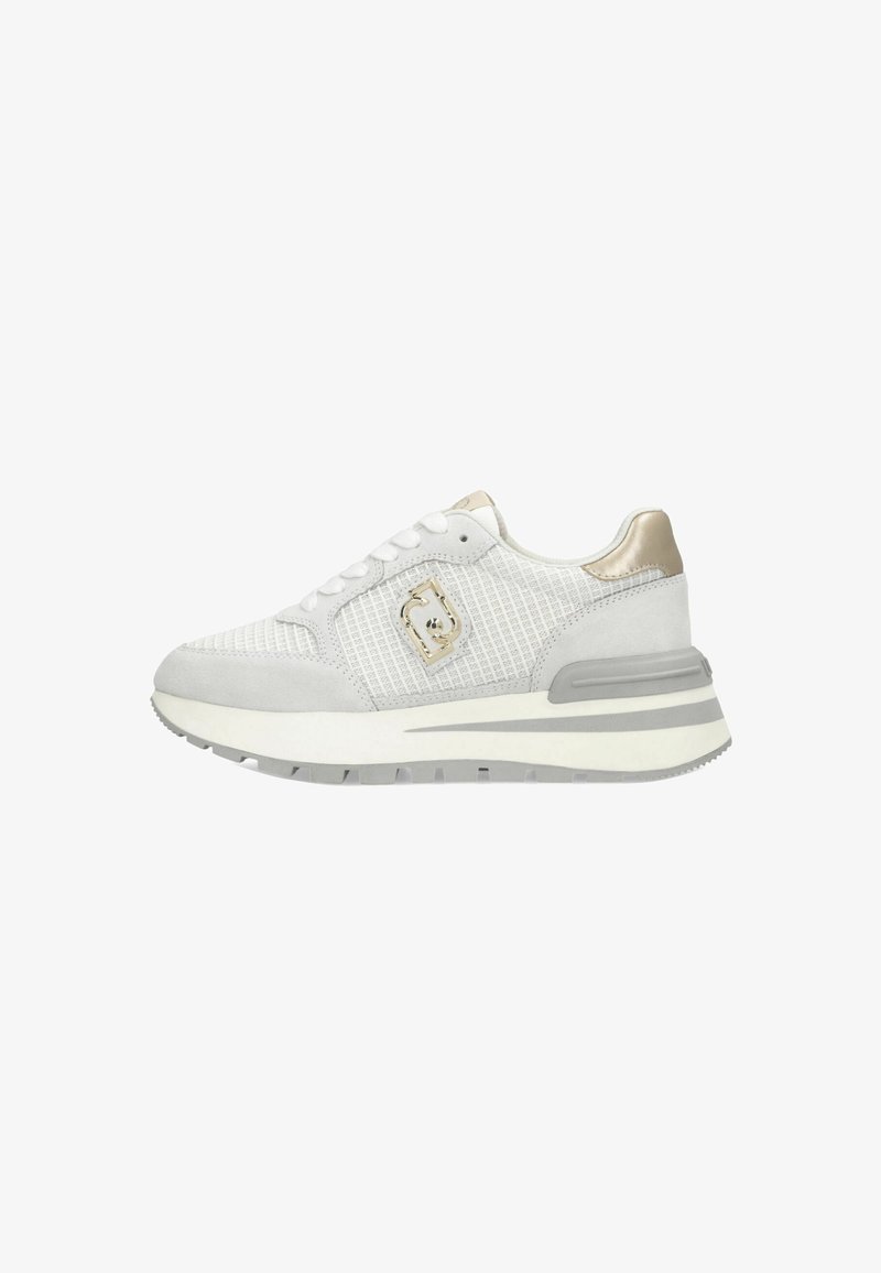 Zapatilla deportiva blanca con una parte superior de malla texturizada, acentos de ante gris y un detalle metálico dorado. Presenta una suela gruesa y acolchada.