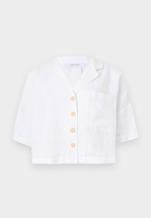 Chemise blanche en lin à manches courtes avec quatre boutons beiges, une poche poitrine et un col cranté, étiquetée DKNY.