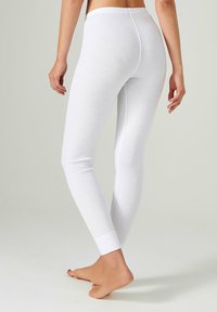 Leggings de algodón blanco con una textura suave, diseño ajustado y puños en los tobillos, que cuentan con una cinturilla de altura media y sin patrones visibles.