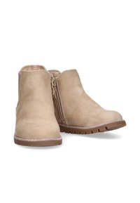 Botines de ante beige con cremallera lateral, suela de goma, acento brillante a lo largo de la suela exterior, punta redondeada y una textura suave.