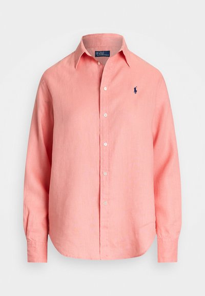 Camisa de manga longa, com botões, em linho rosa claro, com colarinho clássico e um logo azul-marinho no lado esquerdo do peito. Textura suave, ajuste descontraído.