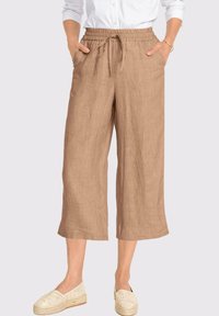 Hellbraune Leinen-Culottes mit einem elastischen Taillenbund, einem Kordelzugdetail und Seitentaschen. Kombiniert mit hellen Espadrilles.