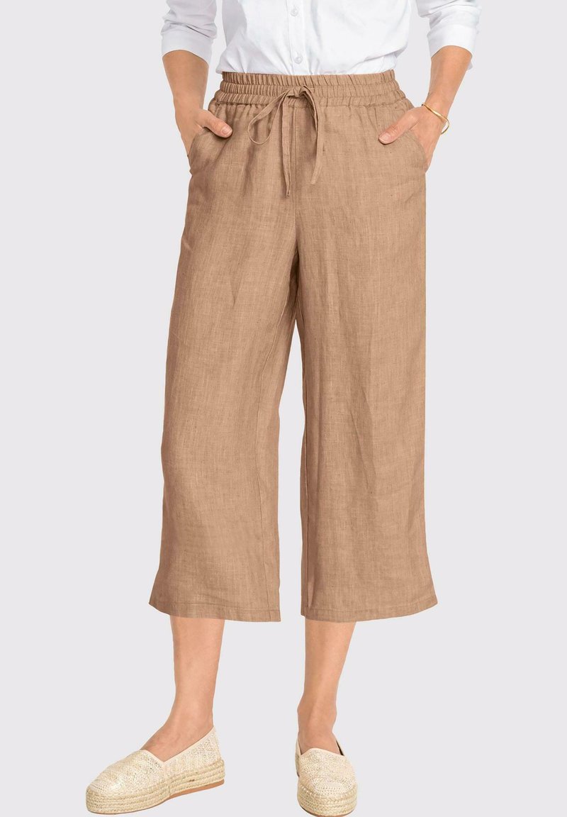 Hellbraune Leinen-Culottes mit einem elastischen Taillenbund, einem Kordelzugdetail und Seitentaschen. Kombiniert mit hellen Espadrilles.